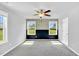 Bright bedroom with two windows, ceiling fan, and accent wall over the carpeted floor at 28 Sandcastle Ln, Four Oaks, NC 27524