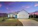 Beautiful, white single-story home with a large garage and a well-manicured lawn underneath a dramatic sky at 28 Sandcastle Ln, Four Oaks, NC 27524