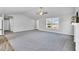 Spacious living room featuring gray walls, plush carpeting, ceiling fan, and natural light from large windows at 28 Sandcastle Ln, Four Oaks, NC 27524