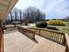 Spacious stained wooden deck with railings offering serene views of the surrounding landscape and mature trees at 3015 Nc Hwy 87 South, Graham, NC 27253