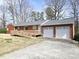 Rear exterior showcasing a two-car garage, brick exterior, wooden deck and ramp with beautiful, mature trees surrounding it at 3015 Nc Hwy 87 South, Graham, NC 27253
