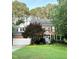 Charming two-story brick home featuring a manicured lawn, lush trees and a delightful periwinkle front door at 307 Kellyridge Dr, Apex, NC 27502