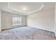 Spacious bedroom featuring neutral paint, gray carpet, a sunlit window, and trey ceilings at 3162 Retama Run # 231, Apex, NC 27562