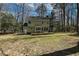 Back exterior view of the house featuring a wooden deck, mature trees, and a spacious lawn at 3313 Ventura Cir, Wake Forest, NC 27587