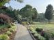 Beautiful backyard featuring a brick walkway, lush landscaping, and a view of the surrounding property at 3417 Pea Ridge Rd, New Hill, NC 27562