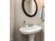 Cozy bathroom with a sleek pedestal sink, round mirror, and towel hanger, providing a simple yet stylish space at 345 Anterbury Dr, Apex, NC 27502
