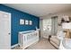 Bedroom featuring blue accent wall, white crib, and cozy reading chair at 345 Anterbury Dr, Apex, NC 27502