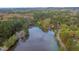 Beautiful aerial view of a serene lake surrounded by lush green trees and colorful autumn foliage at 4117 Olde Coach Rd, Durham, NC 27707