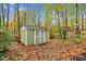 Backyard view of green storage shed with white doors sitting amongst the leaves and trees at 4117 Olde Coach Rd, Durham, NC 27707