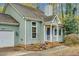 Exterior view of a home featuring muted green siding, mature landscaping, and a white trimmed front porch at 4117 Olde Coach Rd, Durham, NC 27707