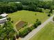 Aerial shot showcases a pond, lush greenery, a barn, and a greenhouse on the property at 4811 New Sharon Church Rd, Hillsborough, NC 27278