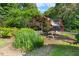 Charming home with lush landscaping, mature trees, and a tranquil garden area with stone bench seating at 4811 New Sharon Church Rd, Hillsborough, NC 27278