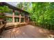 Home's rear exterior shows a brick facade, large windows, a wood deck, and lush greenery at 4811 New Sharon Church Rd, Hillsborough, NC 27278
