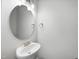 A small powder room features a white pedestal sink and round mirror at 54 Silverleaf Dr, Wendell, NC 27591