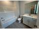 Bright bathroom with tub, grey tile floor, toilet, and white vanity with solid surface top at 5648 Cayden Cove Dr, Wendell, NC 27591