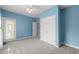 Light blue bedroom featuring a ceiling fan, neutral carpet, and white doors at 6001 Winterpointe Ln # 204, Raleigh, NC 27606