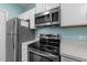 Kitchen with stainless steel appliances, white cabinets, and view of the range at 6001 Winterpointe Ln # 204, Raleigh, NC 27606