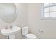 Bright half bathroom features a round mirror, pedestal sink and a white toilet at 65 Hickory Run Ln, Franklinton, NC 27525