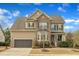 Two-story tan home with brick accents, a manicured lawn, and a two-car attached garage at 8304 Rosiere Dr, Cary, NC 27518