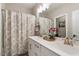 Bright bathroom featuring a double sink vanity, decorative mirror, and neutral patterned shower curtain at 938 Haybeck Ln, Apex, NC 27523