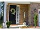 Close-up of front door with beautiful wreath, brick facade, and manicured landscaping at 938 Haybeck Ln, Apex, NC 27523
