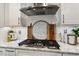 Close-up of a gas cooktop with stainless steel vent hood and decorative backsplash at 938 Haybeck Ln, Apex, NC 27523