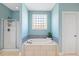 Bright bathroom featuring a tiled tub, glass shower, white door, and a window allowing natural light at 1024 Jensen Grove Ct, Fuquay Varina, NC 27526