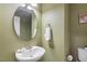 Charming powder room featuring a unique sink, round mirror, modern faucet, and olive-green walls at 1024 Jensen Grove Ct, Fuquay Varina, NC 27526