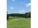 Scenic view of the expansive golf course with lush green grass, mature trees, and a clear blue sky at 105 Olde Liberty Dr, Youngsville, NC 27596