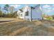 Side exterior view of a modern, renovated house with new siding, dark windows, and a concrete foundation at 111 Faucette Ave, Burlington, NC 27215