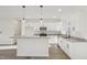Open-concept kitchen featuring sleek white cabinets, a large island, and stainless steel appliances at 111 Faucette Ave, Burlington, NC 27215