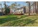 A large green backyard features mature trees, lawn, deck, and privacy fence at 1113 Harvest Mill Ct, Raleigh, NC 27610
