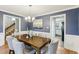 Dining room with blue walls, white wainscoting, wood floors, and adjacent doorway to kitchen at 1113 Harvest Mill Ct, Raleigh, NC 27610