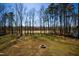 Backyard view featuring mature trees, a fire pit, and spacious lawn at 169 Black Cloud Dr, Louisburg, NC 27549