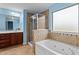 Bright bathroom with a glass-enclosed shower, a tub, neutral tile, and cherry cabinets at 241 Westgrove Ct, Durham, NC 27703