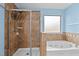 Bright bathroom featuring a glass-enclosed shower, a tub, and neutral tile at 241 Westgrove Ct, Durham, NC 27703