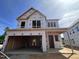 Two-story home under construction featuring a two-car garage and a modern architectural design against a bright blue sky at 243 Meadowbark Bnd # 28, Garner, NC 27529