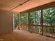 Open porch has natural wood flooring and railing with a view of the tree-lined backyard at 249 High Ridge Ln, Pittsboro, NC 27312