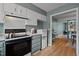 Cozy kitchen featuring white cabinets, black appliances, and a glimpse into the next room at 3080 Colony Rd # A, Durham, NC 27705