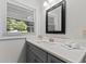 Bright bathroom features a gray vanity with white countertop, modern fixtures, and natural light from a window at 3605 Octavia St, Raleigh, NC 27606