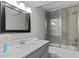 Modern bathroom features a framed mirror, vanity with sink, and a tiled shower-over-tub with glass doors at 3605 Octavia St, Raleigh, NC 27606