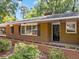 Close up of the brick home's entrance with dark shutters and a small flower bed at 3605 Octavia St, Raleigh, NC 27606