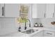 Bright kitchen features a stainless steel sink, modern faucet, white cabinets, and stylish backsplash tiles at 409 Avery St, Garner, NC 27529