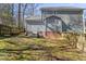 View of a backyard with patchy grass, trees, a weathered wooden fence, and the house's exterior at 6008 Chittim Ct, Raleigh, NC 27616