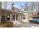 Exterior view of a home with french doors opening onto a patio area with seating, and a partially visible pool at 609 Brookview Dr, Chapel Hill, NC 27514