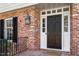 Close-up of a classic black front door with sidelights, set in a brick surround with a stylish lantern at 609 Brookview Dr, Chapel Hill, NC 27514