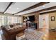 Cozy living room features exposed wood beams, a brick fireplace, and large windows offering natural light at 609 Brookview Dr, Chapel Hill, NC 27514