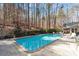 Serene backyard setting with a rectangular pool, patio furniture, and a backdrop of mature trees for privacy at 609 Brookview Dr, Chapel Hill, NC 27514