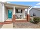 Inviting front porch with brick accents, seating, and a vibrant teal front door at 75 E Moss Creek Dr, Clayton, NC 27520