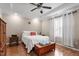 Cozy bedroom featuring a ceiling fan, hardwood floors, a dresser, a chest and a large window for natural light at 75 E Moss Creek Dr, Clayton, NC 27520
